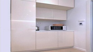 Una cocina con alacenas blancas, un microondas y una cesta sobre la encimera.
