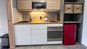 Eine kompakte Küche mit integriertem Mikrowellenherd, einer Spüle und einem roten Kühlschrank.
