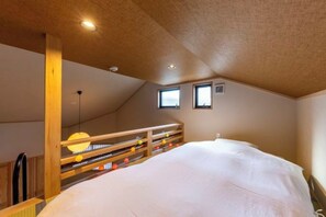Un dormitorio con una cama litera, cabecera de madera, una ventana pequeña y una lámpara en el techo.