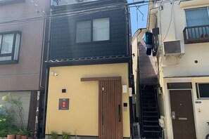 Un immeuble résidentiel avec une porte en bois, un escalier et un petit balcon.