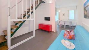 A modern apartment with a staircase, a dining area, and a living room with a sofa.