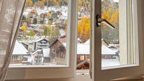 A window with a view of a snowy mountain landscape and a town below. - Lovely apartment for 6 people with WIFI, TV and balcony (Leukerbad)