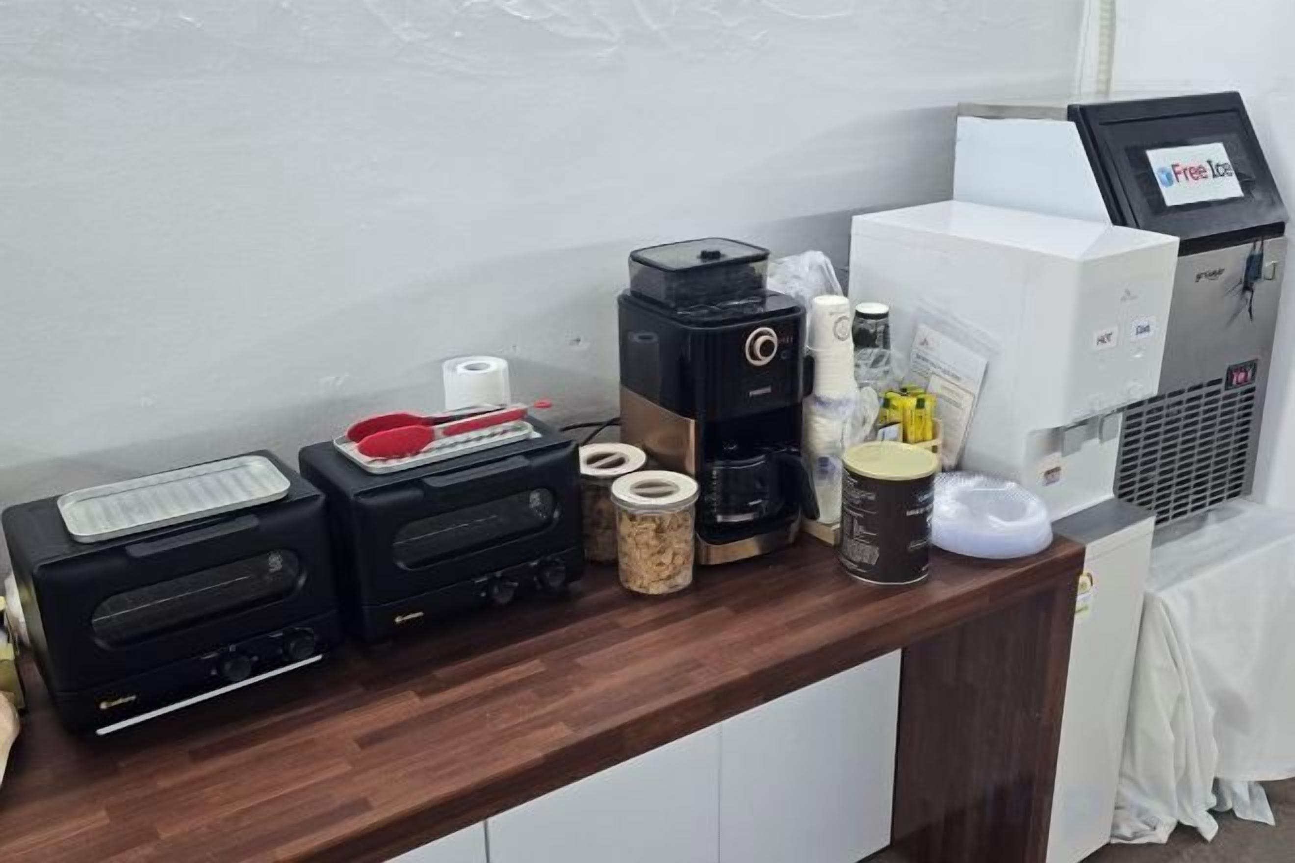 A coffee station with a coffee maker, a scale, and various coffee cups and containers.