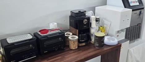 Una estación de café con cafetera, balanza y diferentes tazas y recipientes para café.