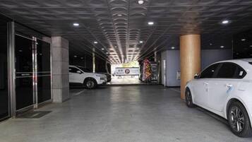 A parking garage with two white cars parked, a pillar, and a sign with text.