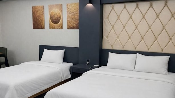 Ett hotellrum med två separata sängar, en sänggavel med ett diamantmönster och tre konstverk som hänger på väggen.