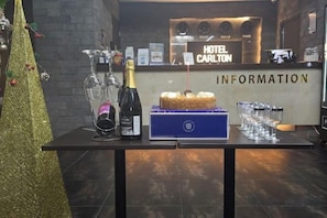 A reception desk with a sign reading 'HOTEL CARLTON INFORMATION' and a table with a cake, champagne, and glasses. - Carlton Hotel (Incheon)