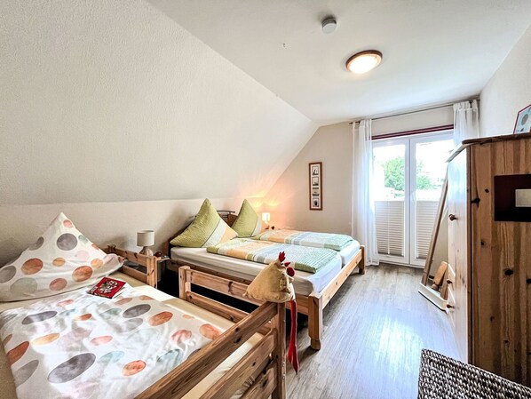 Une chambre confortable avec deux lits en bois, une armoire en bois et une fenêtre avec des stores.