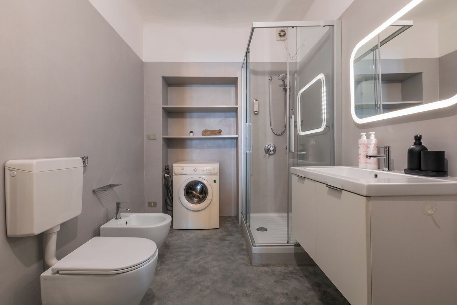 Ein modernes Badezimmer mit Toilette, Waschmaschine und Dusche.