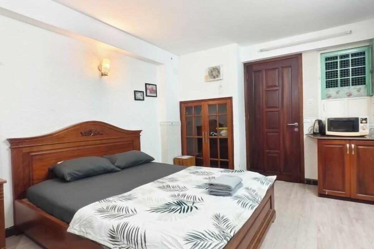 Un dormitorio con cama de madera, armario, mesita y microondas.