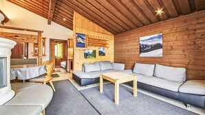 Een gezellige kamer met een houten plafond, een bank, een tafel en een bankje.