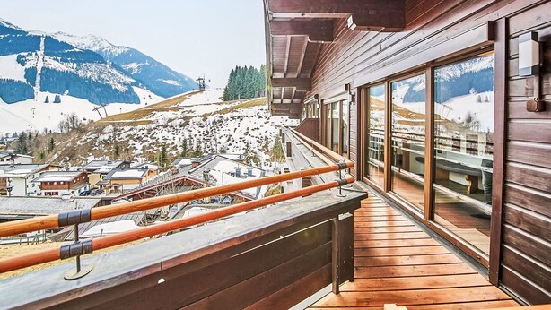 Een houten balkon met uitzicht op een besneeerd berglandschap.