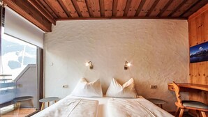 Een slaapkamer met een groot bed, twee kussens, een houten hoofdbord, een kleine tafel en een stoel.