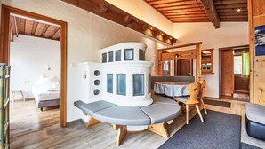 Een knus vertrek met een houten plafond, een inbouwfornuis, een eettafel en een bank.