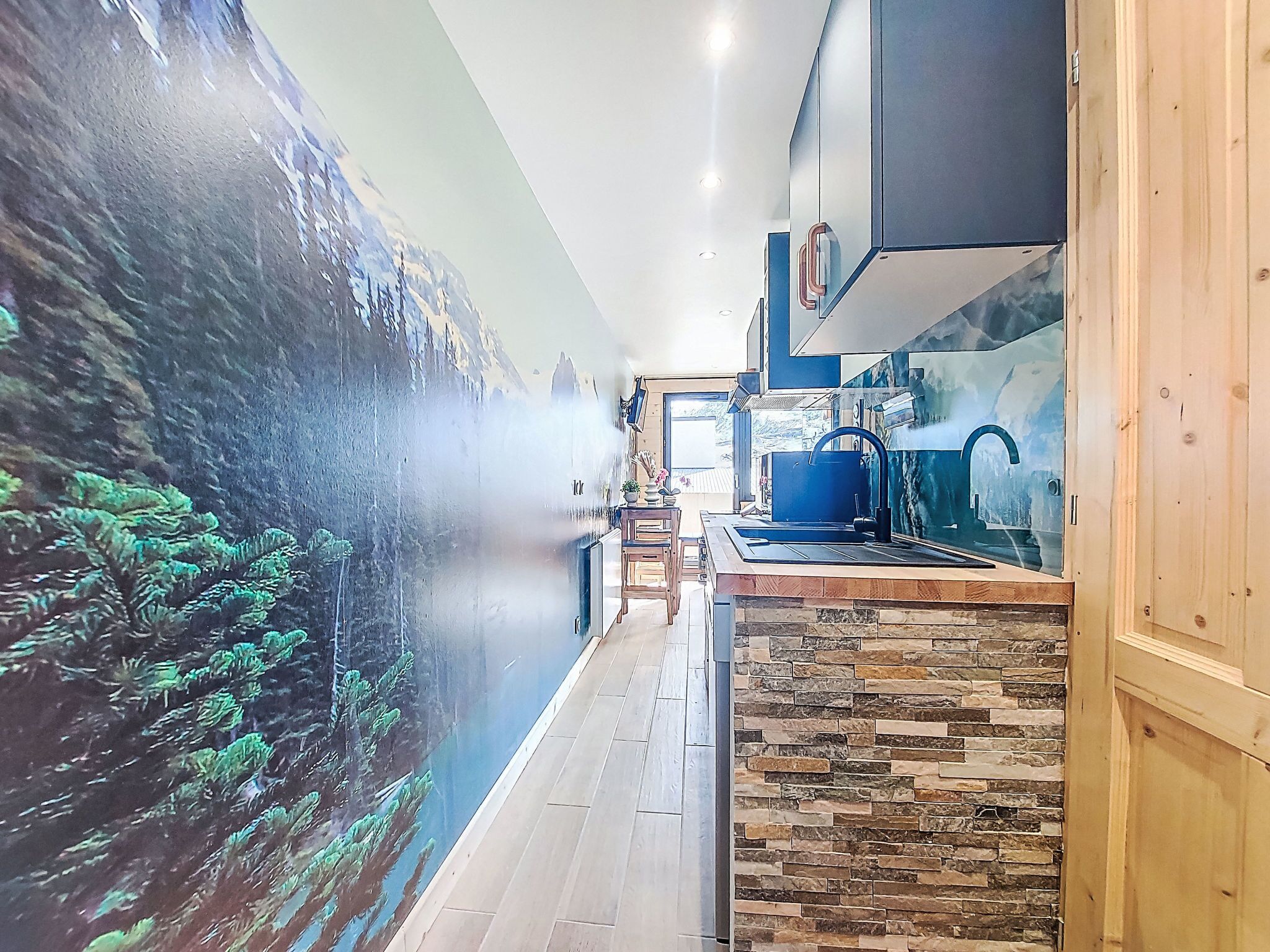A modern kitchen with a stone backsplash, wooden cabinets, and a blue faucet.