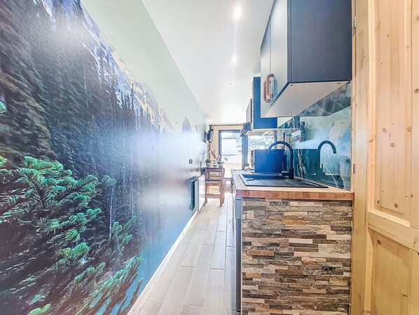 Una cocina moderna con salpicadero de piedra, armarios de madera y grifo azul.