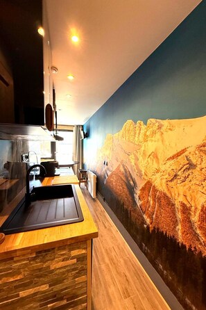 A kitchen with a wooden countertop, a sink, and a wall-mounted stove.