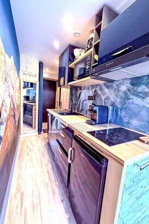 A modern kitchen with a wooden countertop, built-in appliances, and a marble backsplash. - Les Olympiades by Interhome (Val Thorens)