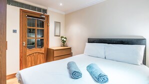 A hotel room with a large bed, a wooden wardrobe with glass doors, a bedside table with a vase of flowers, and a framed picture on the wall. - Frobost Lodge by Interhome (South Uist)