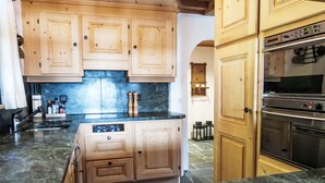 A kitchen with wooden cabinets, a marble countertop, and a built-in oven.