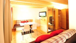 A wooden interior with a sofa, a TV, and a glass-enclosed shower area.
