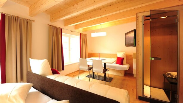 A hotel room with a bed, a desk, a chair, a sofa, and a television.