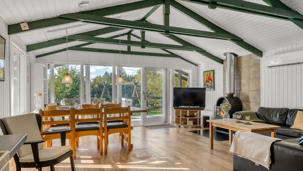 A spacious living area with a wooden floor, a television, a fireplace, and a dining area with wooden furniture. - "Inola" - 3.5km from the sea by Interhome (Fjerritslev)
