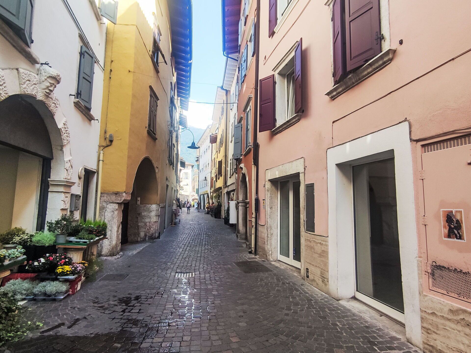 Una estrecha calle adoquinada bordeada por edificios con puertas arqueadas y contraventanas.