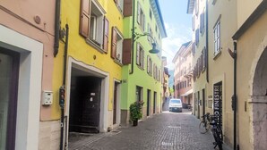 A narrow cobblestone street lined with colorful buildings, a parked bicycle, and a car in the distance.