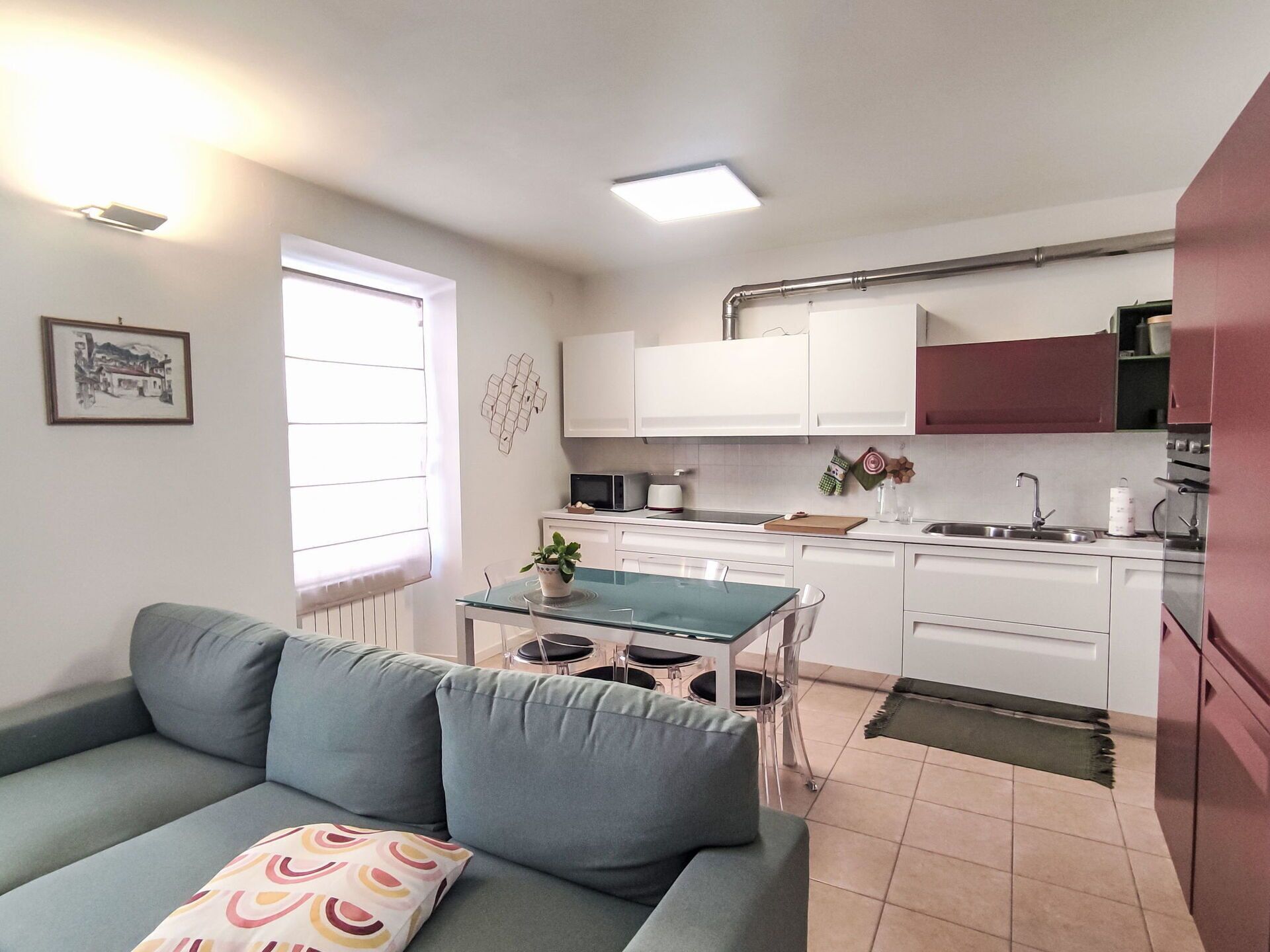 A compact living space with a kitchenette, a dining area, and a sofa with a cushion.