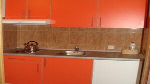 Eine Küche mit orangenen Schränken, einem Edelstahlkocher auf dem Herd und einem Spülbecken.