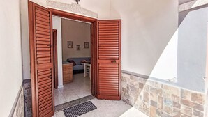 Ein Zimmer mit Holztür, einem kleinen Tisch, einer Couch und einer Wandleuchte.