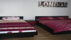 A bedroom with two beds, a wall-mounted artwork with the word "LONDON," and a small bedside table. - Apartments Višnja -  Standard One Bedroom Apartment (Klek)