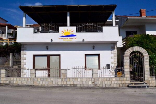 A two-story building with a sign reading "APARTHANE KRAVAC" and a balcony.