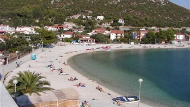 A beach with clear water, a sandy shore, and buildings in the background. - Apartments Višnja -  Standard One Bedroom Apartment (Klek)