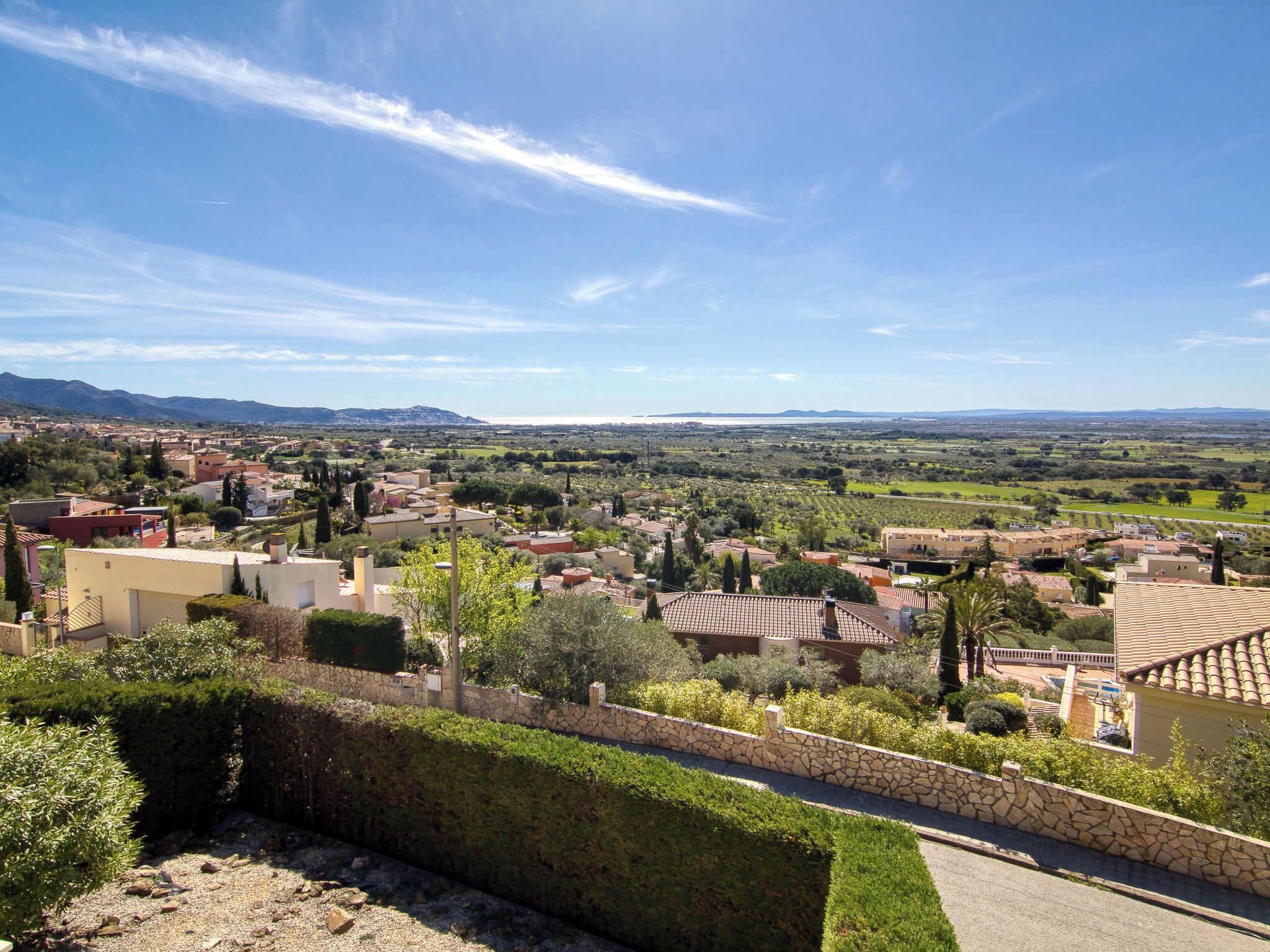 A residential area with houses, a stone wall, and a clear sky.
