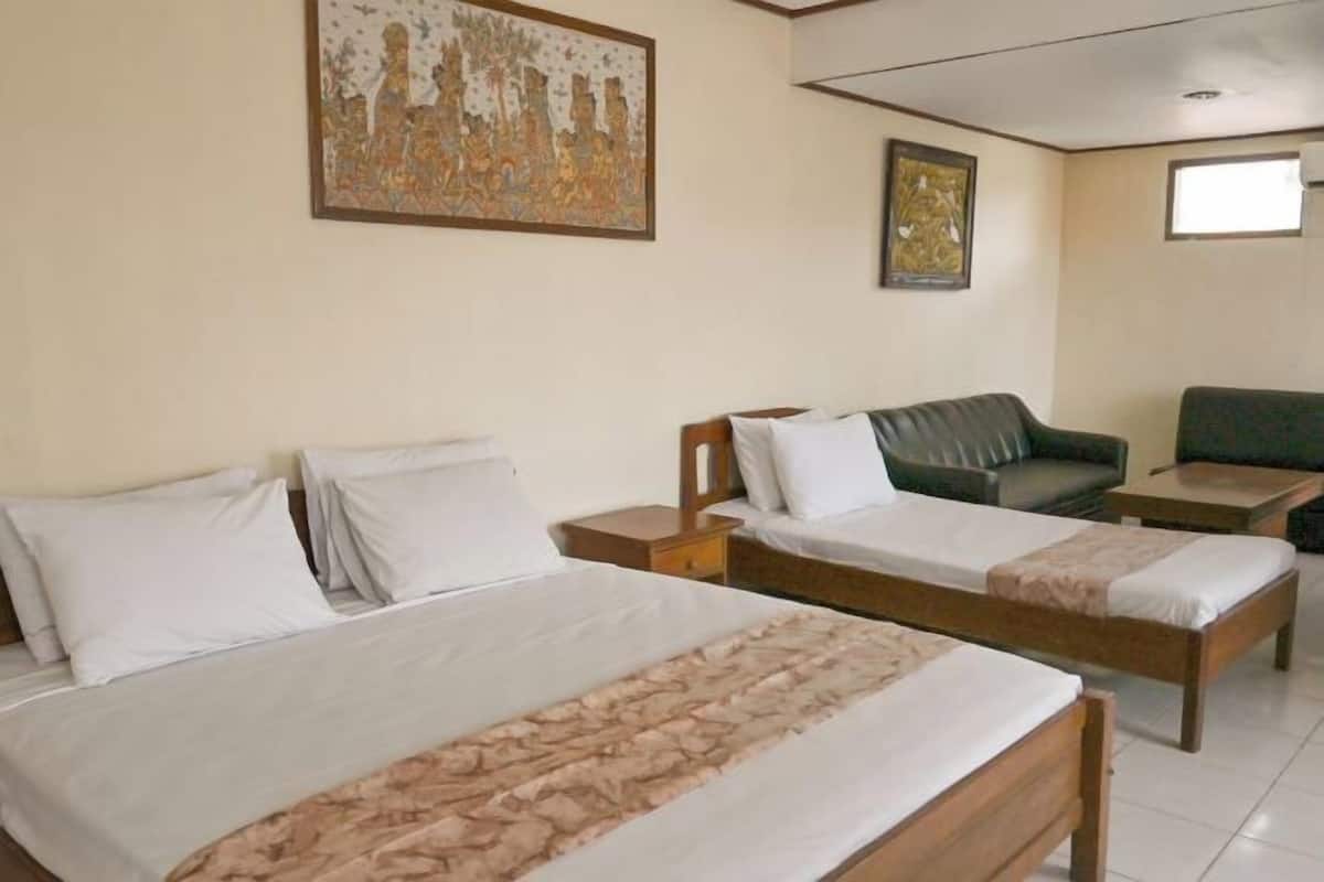 A hotel room with two single beds, a sofa, a small table, and artwork on the walls.