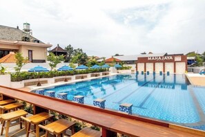A swimming pool with a bar area, a sign reading 'MAHAJAYA', and a view of the surrounding buildings. - Mahajaya Hotel Denpasar (Bali)