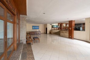 A spacious lobby with a reception desk, a staircase, and a view of the outside. - Mahajaya Hotel Denpasar (Bali)