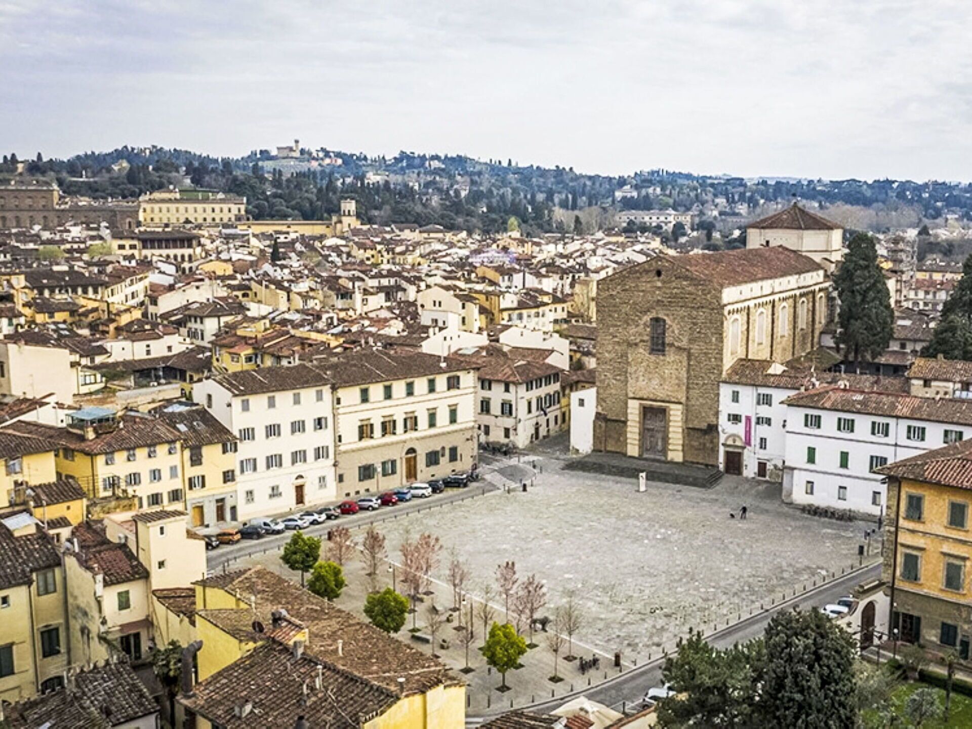 Una plaza histórica con edificios tradicionales, una iglesia destacada y una colina al fondo.