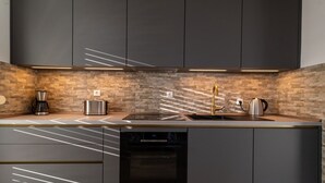 A modern kitchen with dark cabinets, a stone backsplash, and a built-in oven.