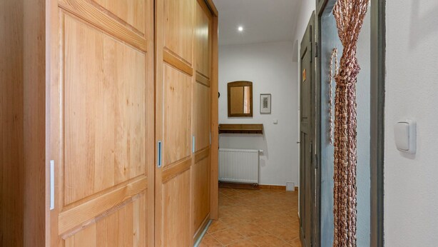 Un corridoio con armadi in legno, un termosifone e uno specchio a parete.