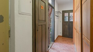 Un corridoio con porte in legno, un muro bianco con un interruttore della luce e un pavimento piastrellato.