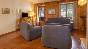 Un salón acogedor con paredes de madera, un televisor, una chimenea y dos sofás grises.