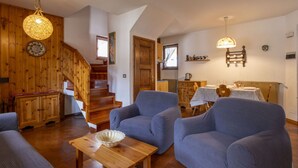 Una sala de estar acogedora con muebles de madera, una escalera y una zona de cocina.
