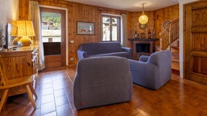 Un salón con suelo de madera, chimenea, televisor y lámpara.
