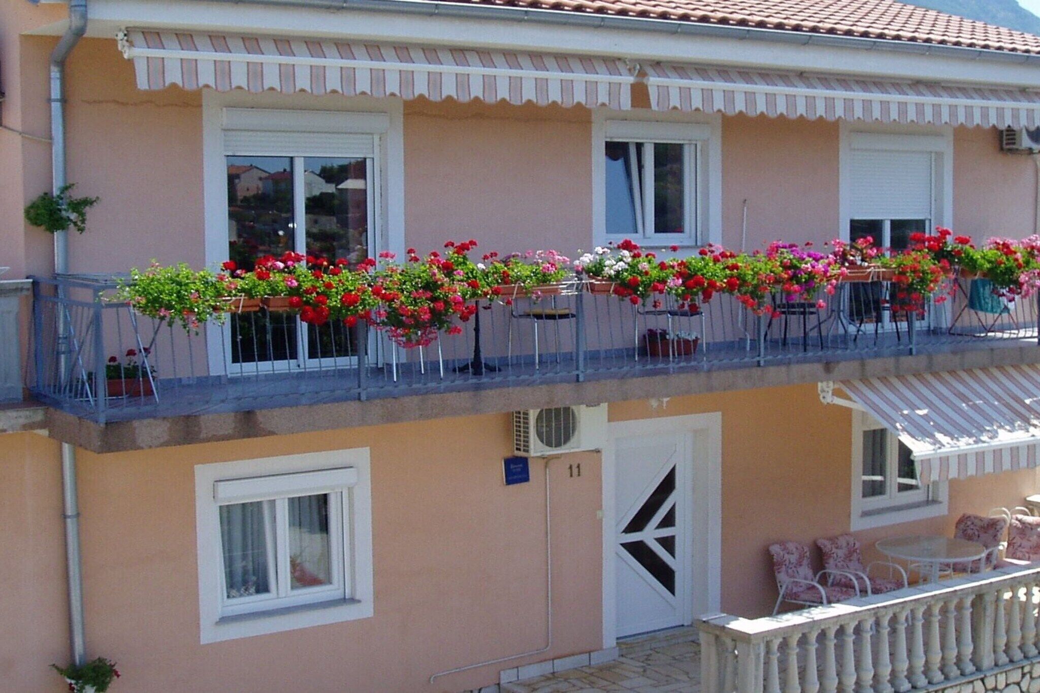 A two-story building with a balcony adorned with flower boxes and outdoor furniture.