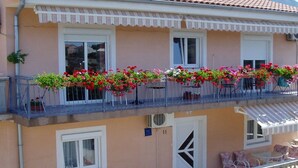 Ein zweistöckiges Gebäude mit einem Balkon, der mit Blumenkästen und Gartenmöbeln dekoriert ist.