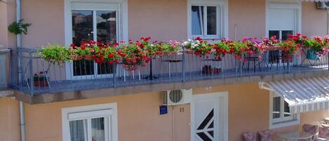 A two-story building with a balcony adorned with flower boxes and outdoor furniture.