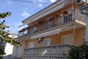 Un edificio de dos plantas con balcones decorados con plantas en macetas.